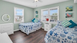 A bedroom with two beds, a ceiling fan, and a window with blinds. - Updated 5 BR Canal Home, Short Walk To Beach! (Ocean Isle Beach)