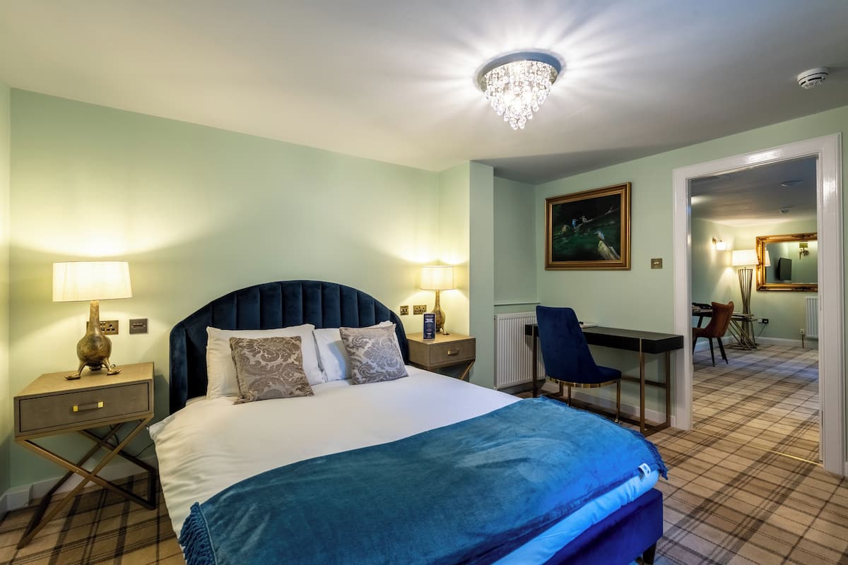 Ein Hotelzimmer mit Bett, Schreibtisch, Stuhl und einer Kristallleuchter.