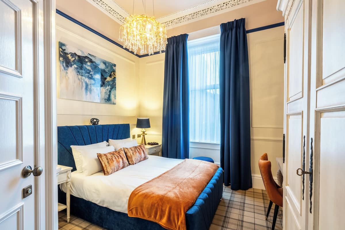 Ein Hotelzimmer mit einem großen Bett, einer Kristallleuchtre, einem Gemälde und Blick nach draußen.