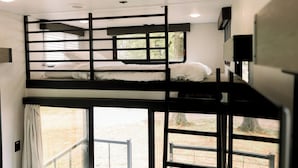 A bunk bed room with a window and a door.