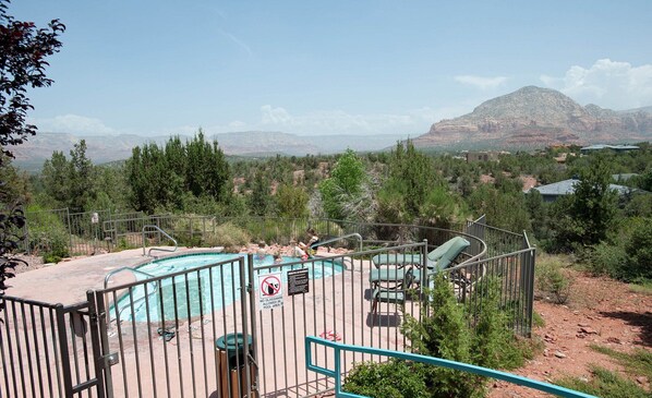 Zona de piscina con vistas a montañas, rodeada por una valla y un cartel que prohíbe el uso de vasos de vidrio.