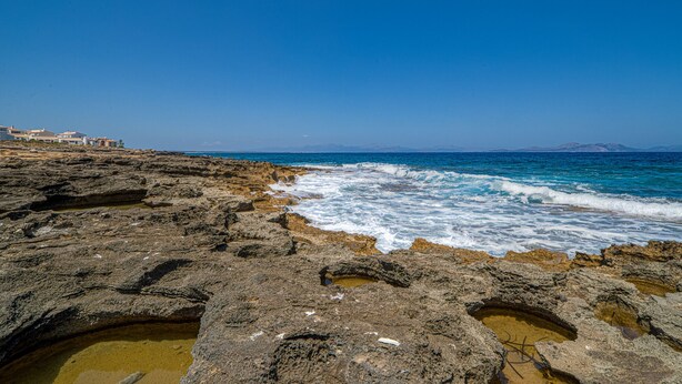 Una costa rocciosa con le onde che si infrangono sulla riva.