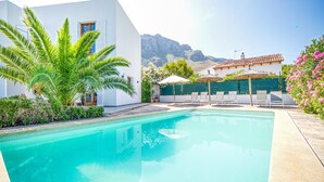 Piscina con lettini e vista sulle montagne sullo sfondo.