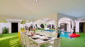 Ein Essbereich mit Pool und grüner Kunstrasen.