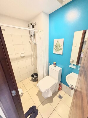 Une salle de bain avec douche, toilettes, lavabo et un mur d’accent bleu.
