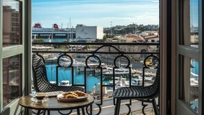 Un balcón con dos sillas y una mesa, con vista a un puerto deportivo con barcos y edificios al fondo.