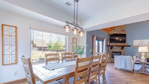Un comedor con una mesa y sillas de madera, una lámpara colgante y una chimenea de piedra.