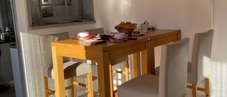 A dining area with a wooden table and chairs, a kitchen area with a microwave, and artwork on the walls.