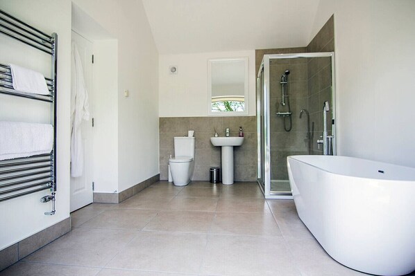 Un baño moderno con ducha a ras de suelo, bañera independiente y retrete.