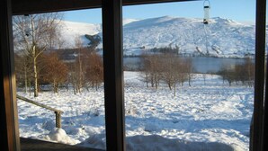 A room with a large window overlooking a snowy landscape with trees and a mountain.