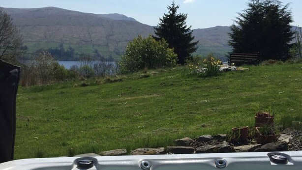 A hot tub with a view of a grassy field and mountains in the background. - Loch Tay Bothy Cottage with Hot Tub (Perth and Kinross)