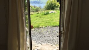 An open door leading to a gravel path and a grassy area with a view of a lake and hills. - Loch Tay Bothy Cottage with Hot Tub (Perth and Kinross)