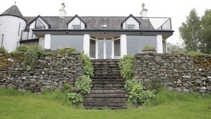 A stone staircase leading to a white building with a grey roof and black railings.