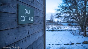 A wooden cottage with a sign reading "OAK COTTAGE" mounted on the wall. - Oak Cottage & Hot Tub, Loch Tay (Perth and Kinross)