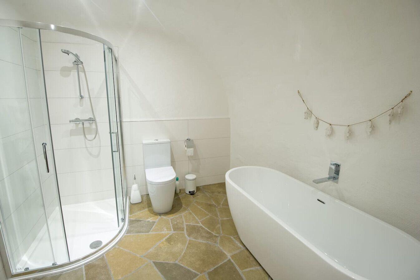 A bathroom with a glass-enclosed shower, a toilet, a bidet, and a freestanding bathtub.