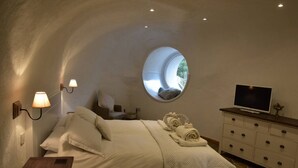 A bedroom with a bed, a round mirror, a television, and a dresser.