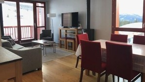 Ein Wohnzimmer mit einer Couch, einem Couchtisch, einem Fernseher und einem Kamin.