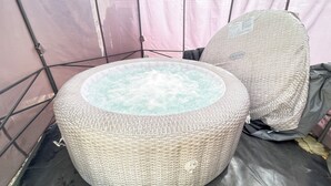 Un bain à remous dont l’extérieur est recouvert d’osier, entouré d’une structure en forme de tente.