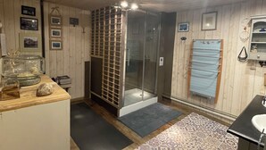 Une salle de bain avec des murs en bois, un espace douche, un lavabo et un sol à motifs.