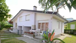 Una casa moderna de dos pisos amb un porxo cobert, un petit jardí i un garatge visible.