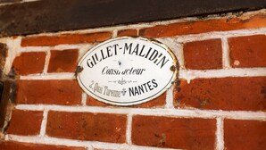 Eine Backsteinmauer mit einem kreisförmigen Schild, das 'Gillet-Maludin Consu acteur 2, Quai Turenne NANTES' zeigt.