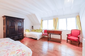 A bedroom with a bed, a desk, a chair, a wardrobe, and a window with curtains.