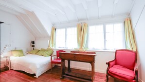 Ein Schlafzimmer mit einem Bett, einem Schreibtisch, einem Stuhl und einem Fenster mit Vorhängen.