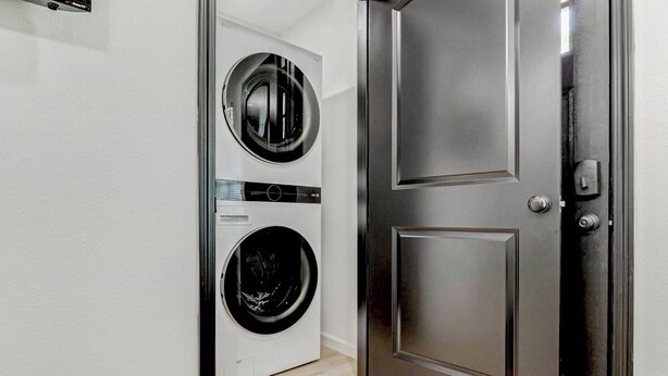 A laundry room with two stacked front-loading washing machines and a closed door. - Welcome to The Pink Peony on Market Street in historic downtown Brenham. (Brenham)