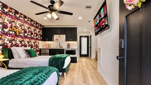 A bedroom with two beds, a ceiling fan, a TV, and a floral wallpaper. - Welcome to The Pink Peony on Market Street in historic downtown Brenham. (Brenham)