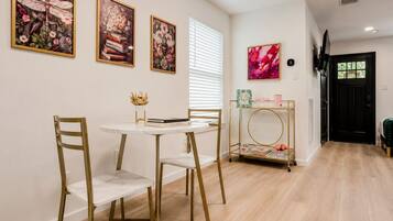 Un comedor con una mesa redonda, dos sillas y un cuadro con marco dorado en la pared.