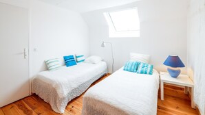Una camera da letto con due letti, un comodino, una lampada e una finestra.