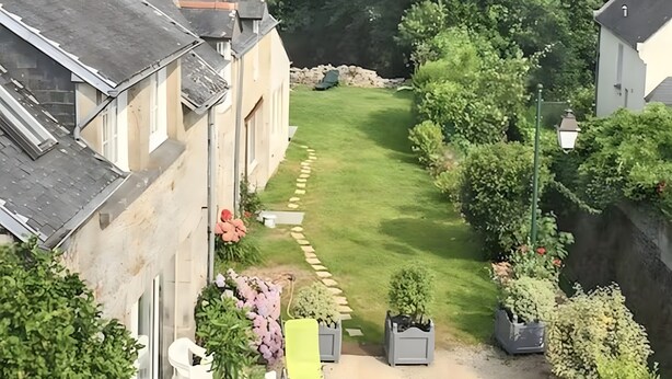 Una zona residenziale con un prato curato, un vialetto e una fila di case con finestre e porte ben visibili.
