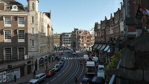 A street view with historic buildings, a tram, and a clear sky.