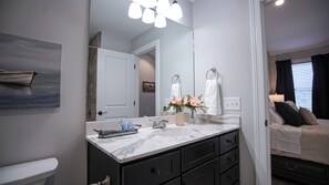 A modern bathroom with a marble sink, dark cabinetry, and a large mirror. - Quiet, Comfort, Safety - 30 min from Nashville. (White Bluff)