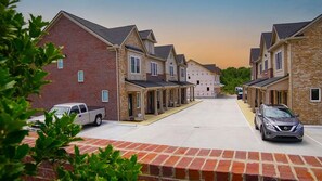 A residential street with brick houses, a driveway, and parked cars. - Quiet, Comfort, Safety - 30 min from Nashville. (White Bluff)