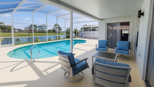 Un espace extérieur abrité avec une piscine, des chaises bleues et une vue sur un lac et des arbres.