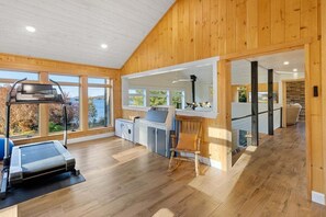 Um quarto amplo com esteira, decoração em madeira, janelas grandes e vista para o exterior.