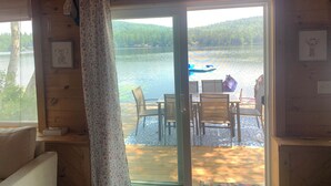 Une cabane en bois dotée d’un coin repas donnant sur un lac, avec une table et des chaises, et des œuvres d’art encadrées accrochées aux murs.