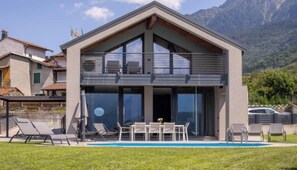 Une maison moderne à deux étages, dotée d’un balcon, d’une piscine et offrant une vue sur les montagnes.