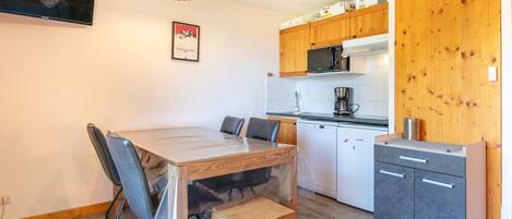 A compact kitchen with a dining area, wooden cabinets, a microwave, and a coffee maker.