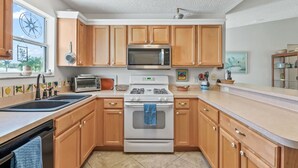 A modern kitchen with wooden cabinets, a stainless steel microwave, a gas stove, and a built-in oven.