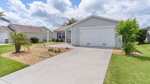 A single-story house with a garage, a driveway, and a well-maintained lawn.