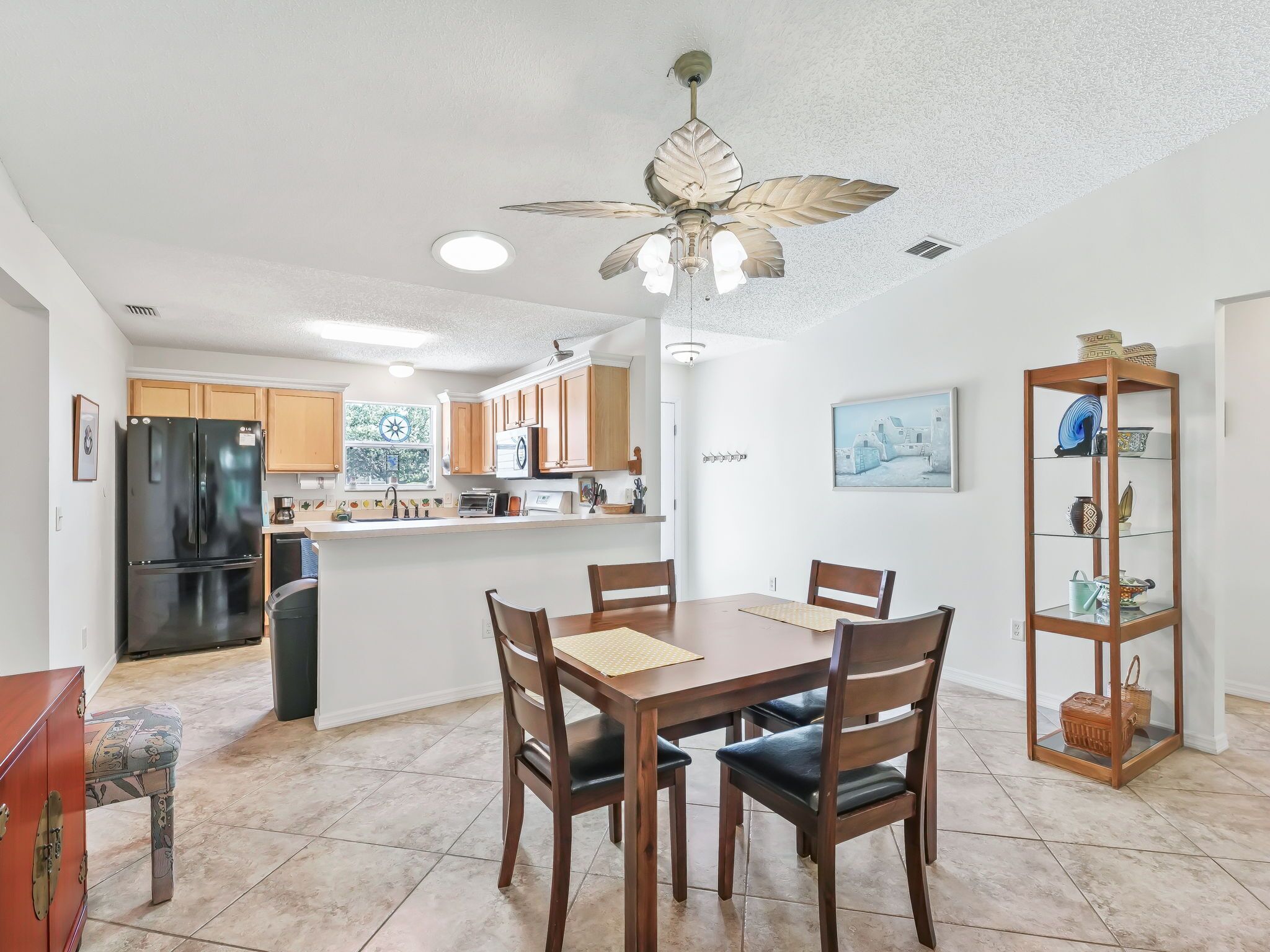 A modern kitchen with wooden cabinets, a black refrigerator, and a dining area with a wooden table and chairs.