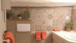 Baño pequeño con inodoro, lavamanos y un salpicadero decorativo.