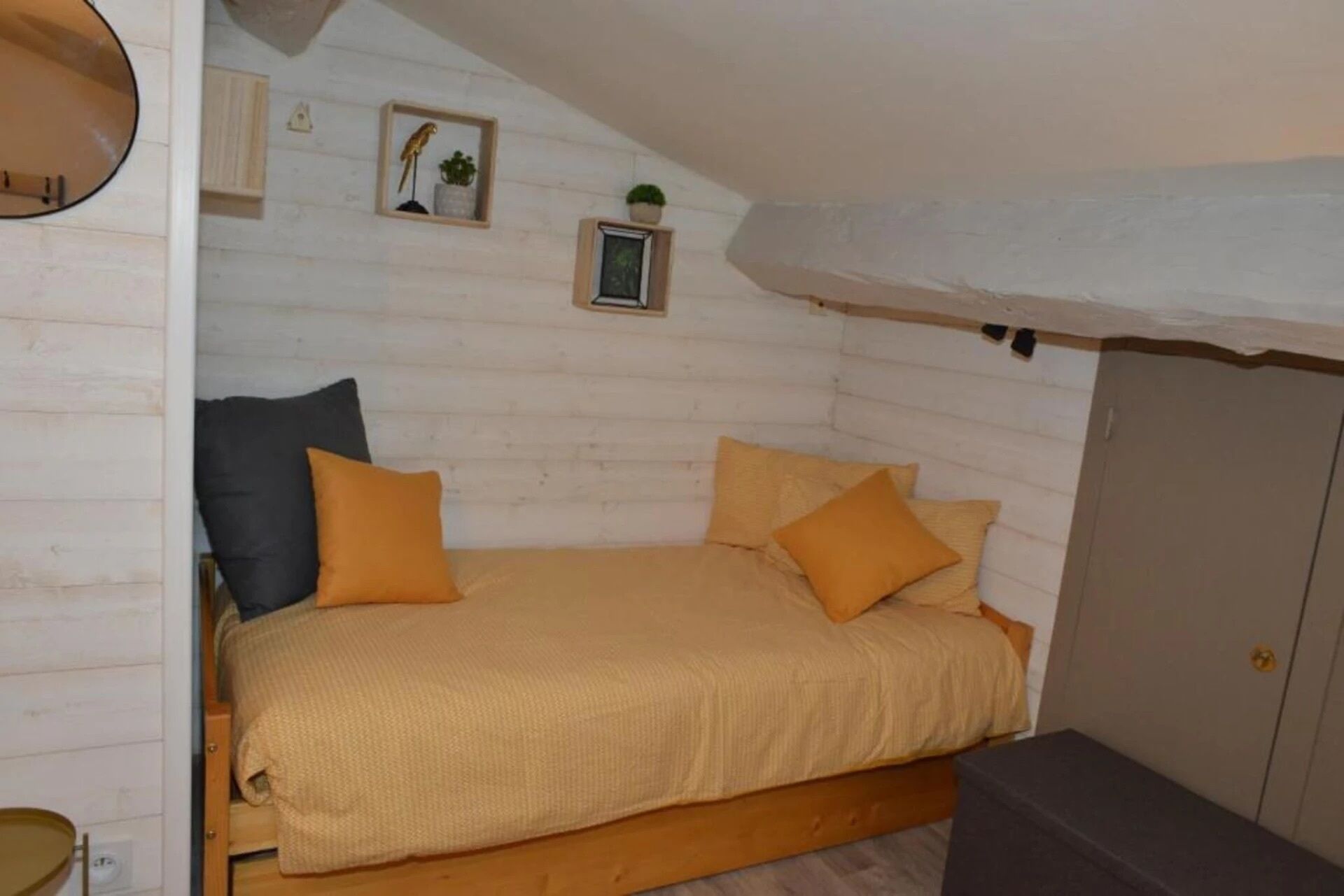 Una camera da letto accogliente e intima con un letto singolo, due cuscini, un comodino e un armadio.
