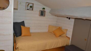 Una camera da letto accogliente e intima con un letto singolo, due cuscini, un comodino e un armadio.