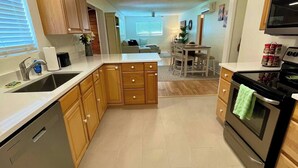 Une cuisine moderne avec des meubles en bois, un lave-vaisselle, une cuisinière et un coin repas comprenant une table et des chaises.