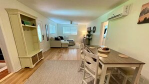 Un vaste espace de vie comprenant une table à manger, des chaises, un canapé et un banc intégré avec espace de rangement.
