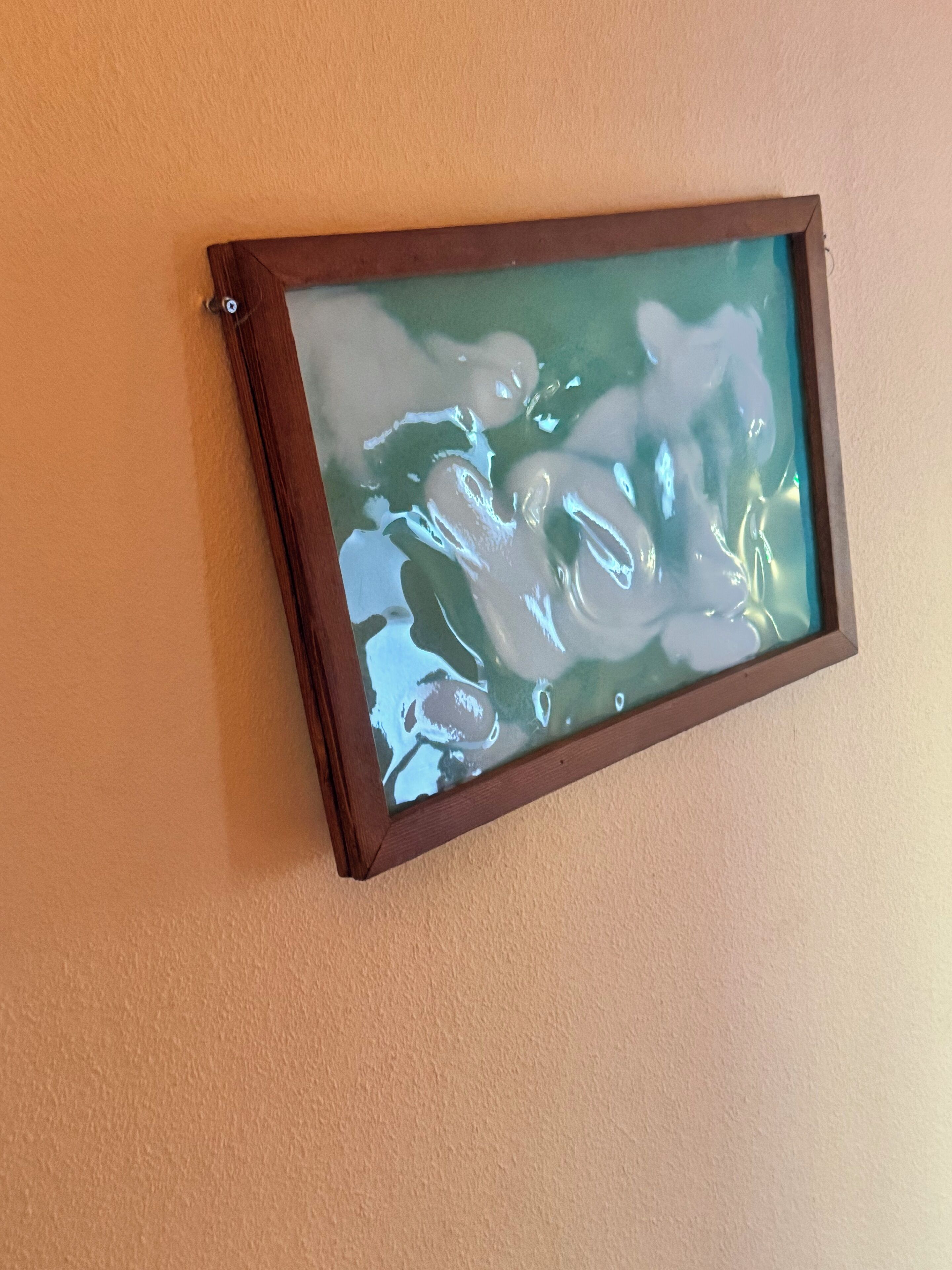 A framed artwork with abstract shapes on a wall.