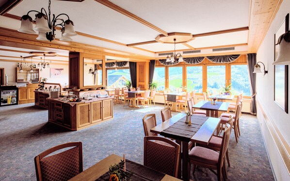 A spacious dining area with wooden furniture and large windows offering a view of the countryside. - Hotel Schauinsland (Bad Peterstal-Griesbach)